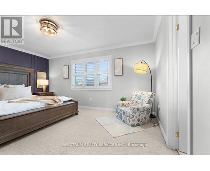 A bedroom with a bed, chair, and window.