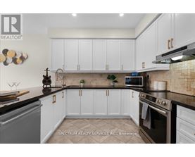 A kitchen with white cabinets and a black countertop.