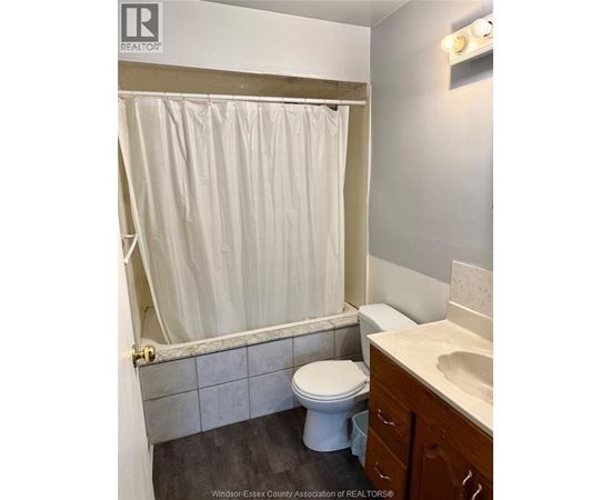A white toilet sits in a bathroom next to a sink.