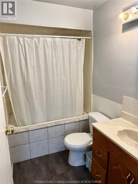 A white toilet sits in a bathroom next to a sink.