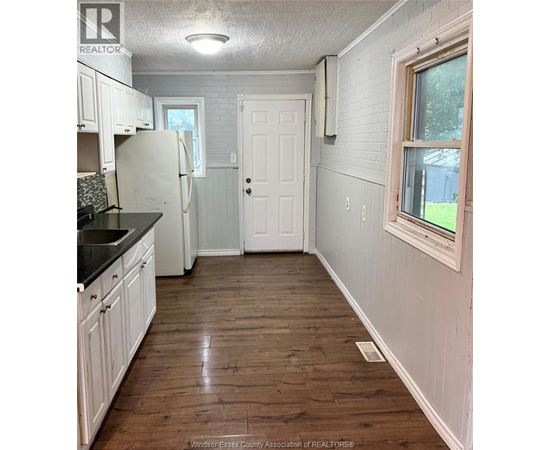 A kitchen with white cabinets and a black counter top.