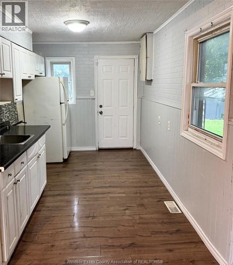 A kitchen with white cabinets and a black counter top.