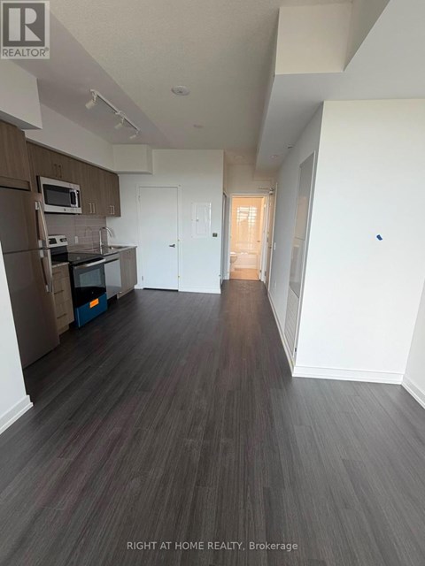 A spacious room with wood flooring and white walls.