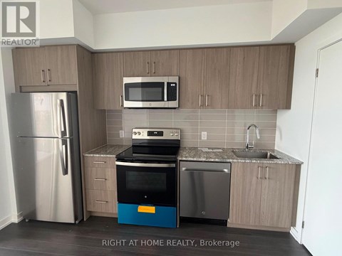 A kitchen with a refrigerator, microwave, oven, and sink.