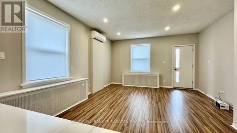 A room with wooden flooring and white walls.