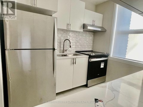 A kitchen with a refrigerator, sink, and cabinets.