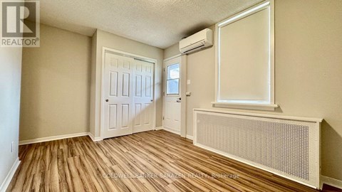 A room with wood flooring and a window with a white frame.