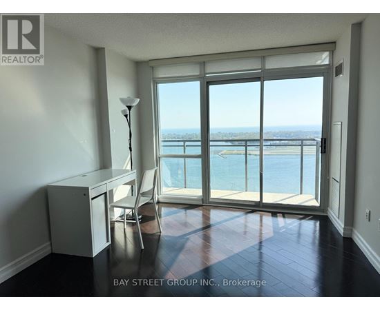 A room with a desk and chair in front of a large window with a view of the water.