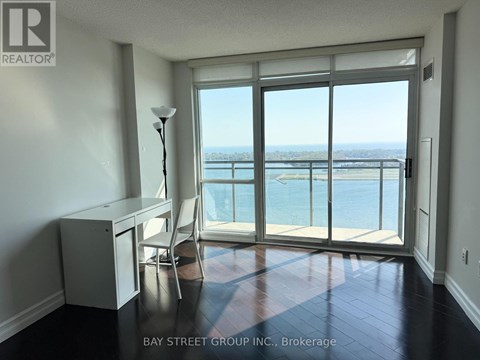 A room with a desk and chair in front of a large window with a view of the water.