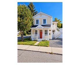 A small white house with a red door and a white picket fence.