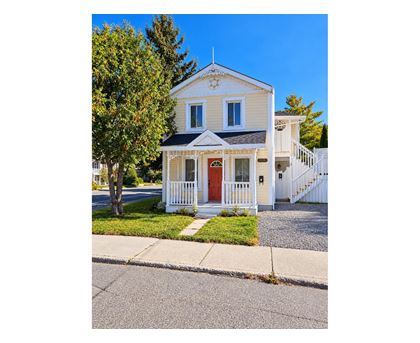 A small white house with a red door and a white picket fence.