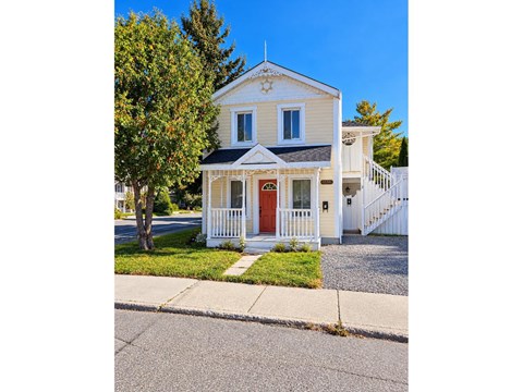 A small white house with a red door and a white picket fence.