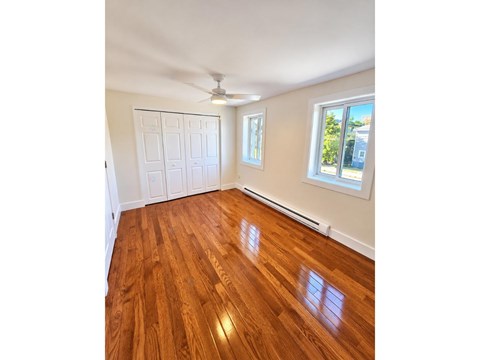 A room with wooden flooring and a ceiling fan.