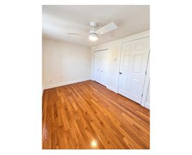 A room with a ceiling fan and wooden flooring.
