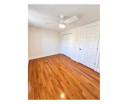 A room with a ceiling fan and wooden flooring.