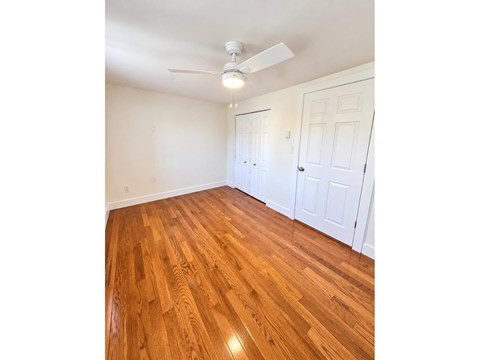 A room with a ceiling fan and wooden flooring.