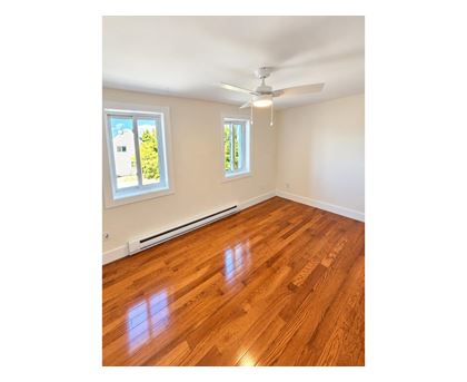 A room with wooden flooring and a ceiling fan.