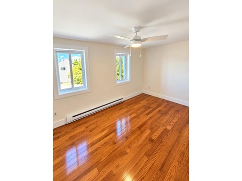 A room with wooden flooring and a ceiling fan.