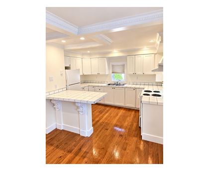 A kitchen with white cabinets and a wooden floor.