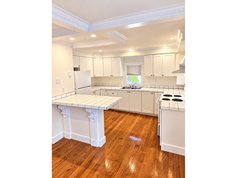 A kitchen with white cabinets and a wooden floor.