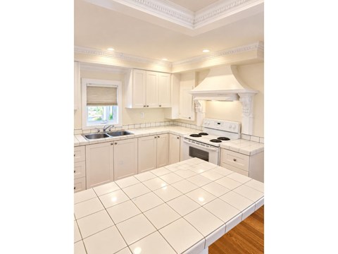 A white kitchen with a tile floor and white appliances.