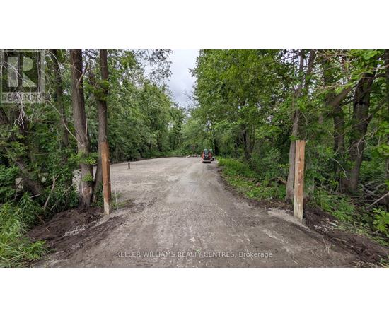 A dirt road with a sign that says "Keller Williams Realty Centres Brokerage" on the left side.
