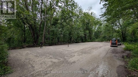 A dirt road with a vehicle on it and trees on both sides.