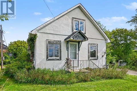 A small white house with a black gable and a balcony.
