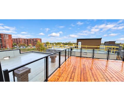 A wooden deck with a glass railing and a metal fence.