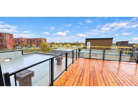 A wooden deck with a glass railing and a metal fence.