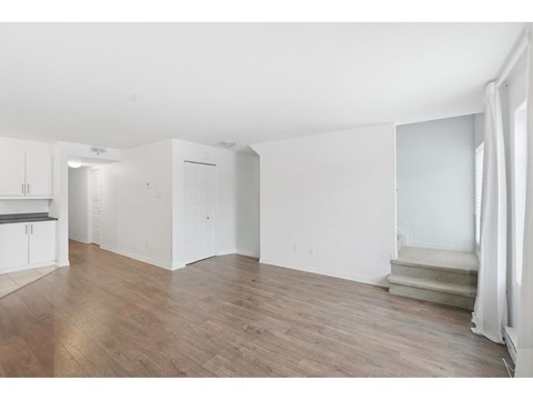 A large empty room with wooden floors and white walls.