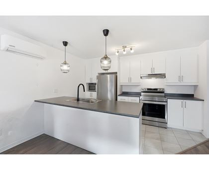 A modern kitchen with a stainless steel island and white cabinets.