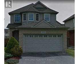 A house with a grey garage door and a sign that says "Royal LePage Trilland Realty, Brokerage".