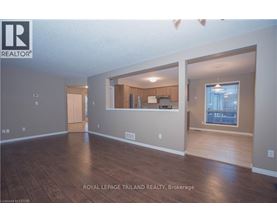 A spacious room with wooden flooring and a large window.
