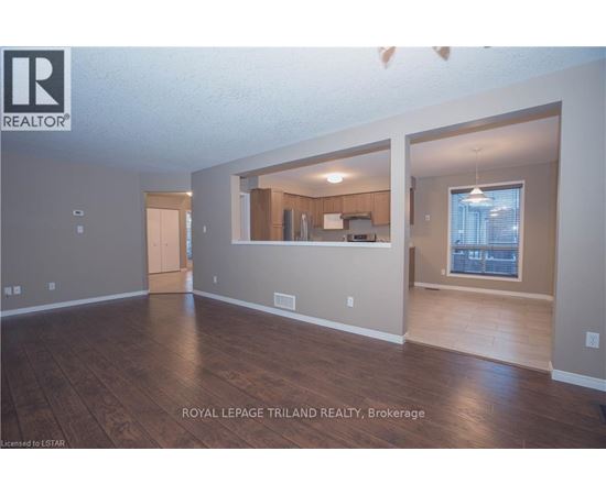 A spacious room with wooden flooring and a large window.