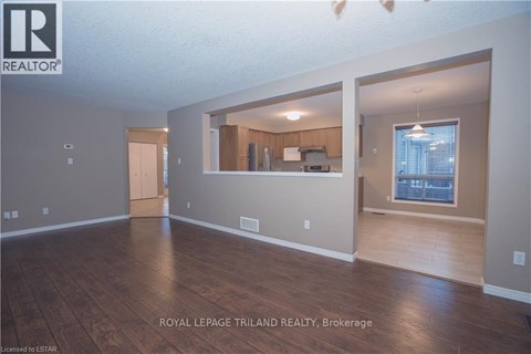 A spacious room with wooden flooring and a large window.