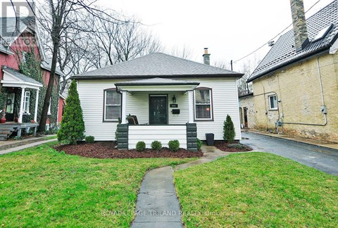 A white house with a grey roof and a small front yard.