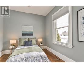 A bedroom with a bed, two lamps, and a painting on the wall.