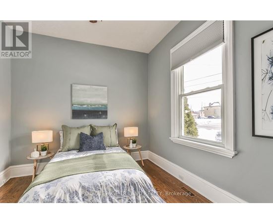 A bedroom with a bed, two lamps, and a painting on the wall.