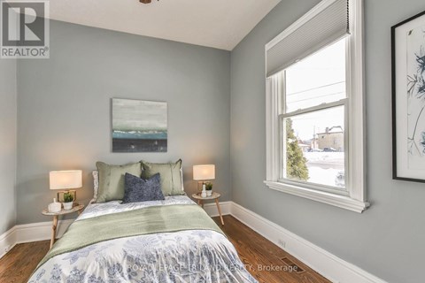 A bedroom with a bed, two lamps, and a painting on the wall.