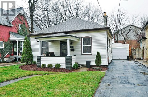 A white house with a grey roof and a small front yard.
