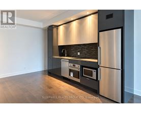 A modern kitchen with stainless steel appliances and wooden flooring.