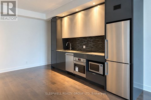 A modern kitchen with stainless steel appliances and wooden flooring.