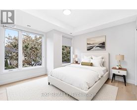 A bedroom with a large bed, a nightstand with a lamp, and a painting on the wall.