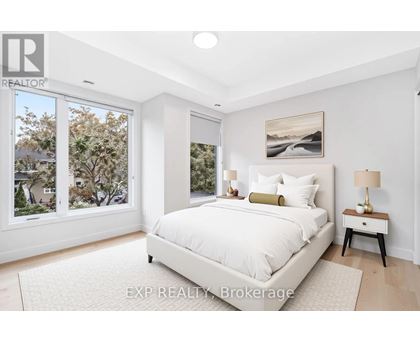 A bedroom with a large bed, a nightstand with a lamp, and a painting on the wall.