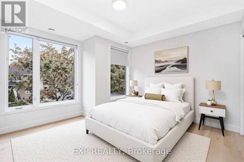 A bedroom with a large bed, a nightstand with a lamp, and a painting on the wall.
