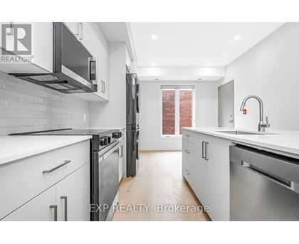 A modern kitchen with white cabinets and stainless steel appliances.