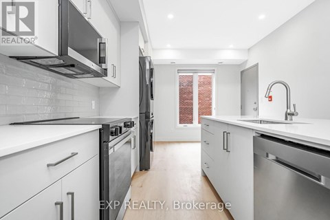 A modern kitchen with white cabinets and stainless steel appliances.