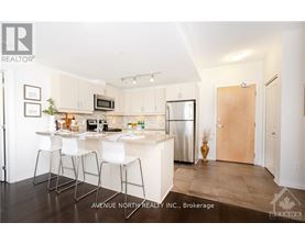 A modern kitchen with white chairs and a wooden door.