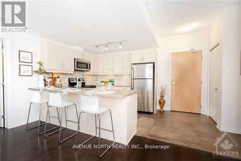 A modern kitchen with white chairs and a wooden door.